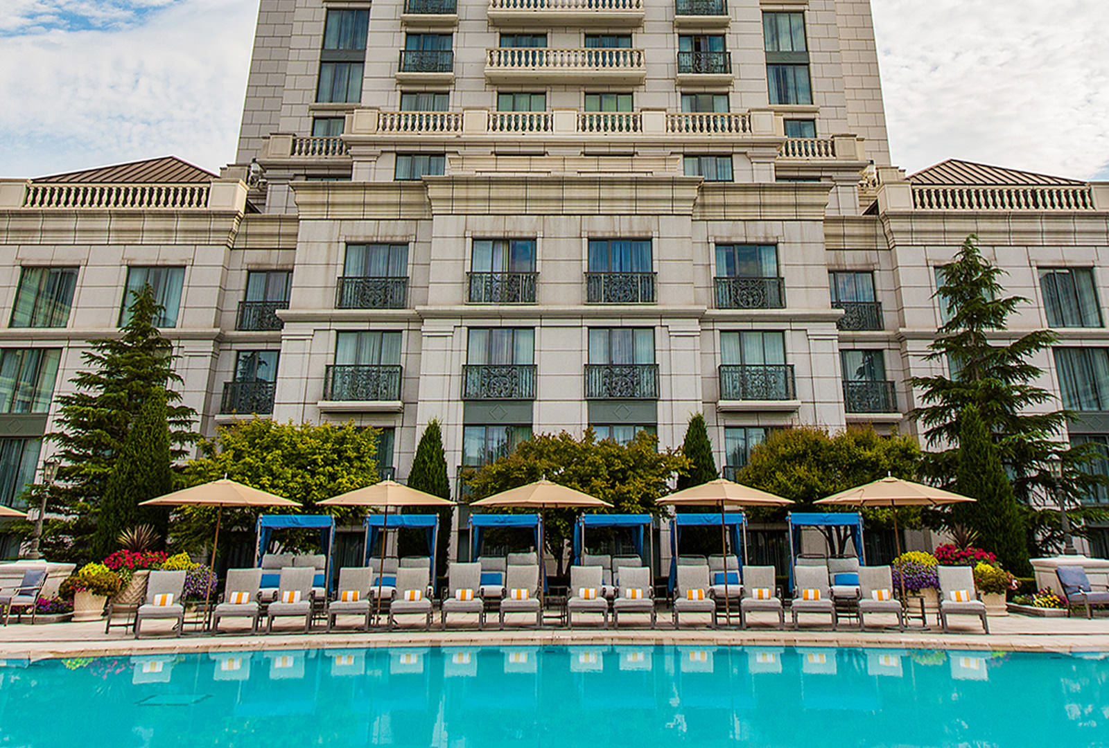 Outdoor hotel pool with yellow umbrellas and blue cabanas