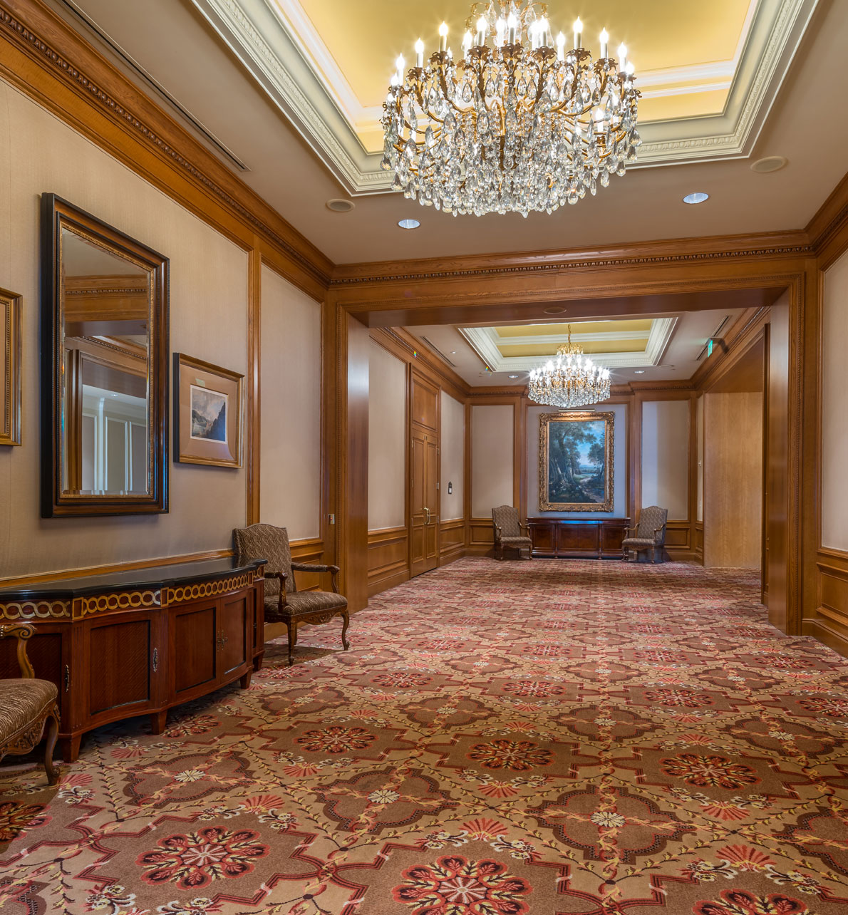Savoy and Envoy reception area at the Grand America Hotel with chandeliers and wood trim.