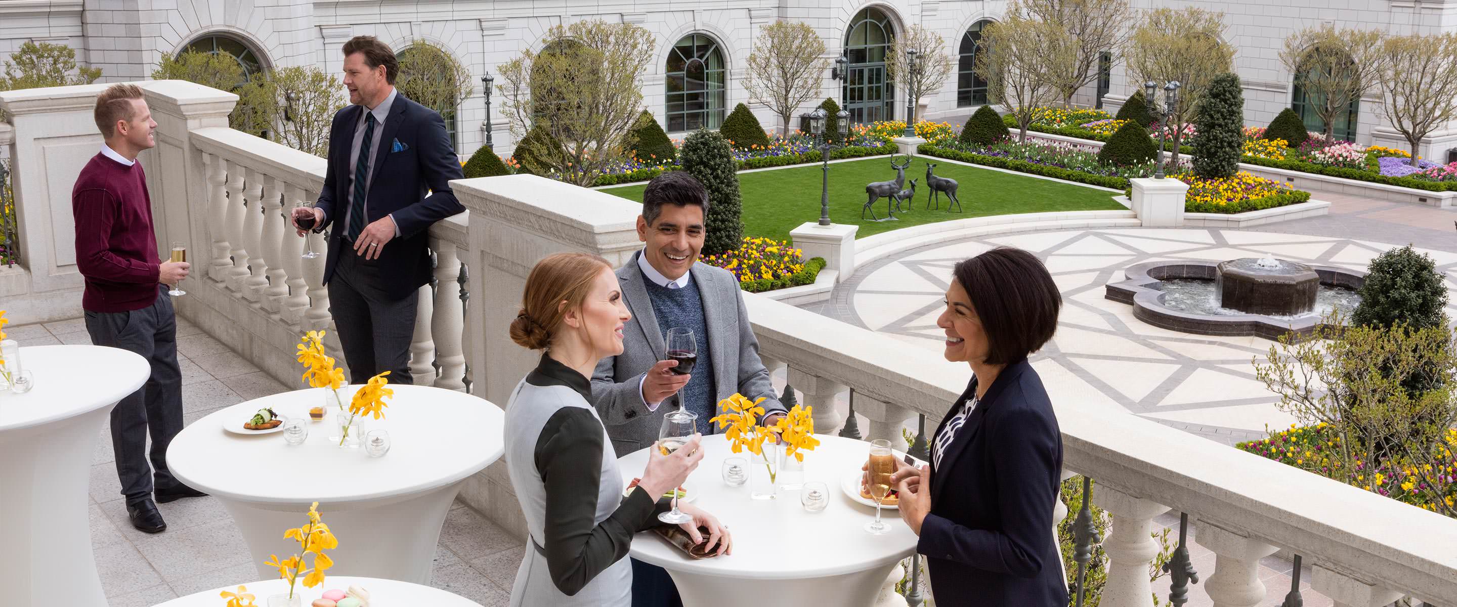 Group of business colleagues at a reception talking and drinking cocktails on the balcony of the third-floor event space at The Grand America Hotel.