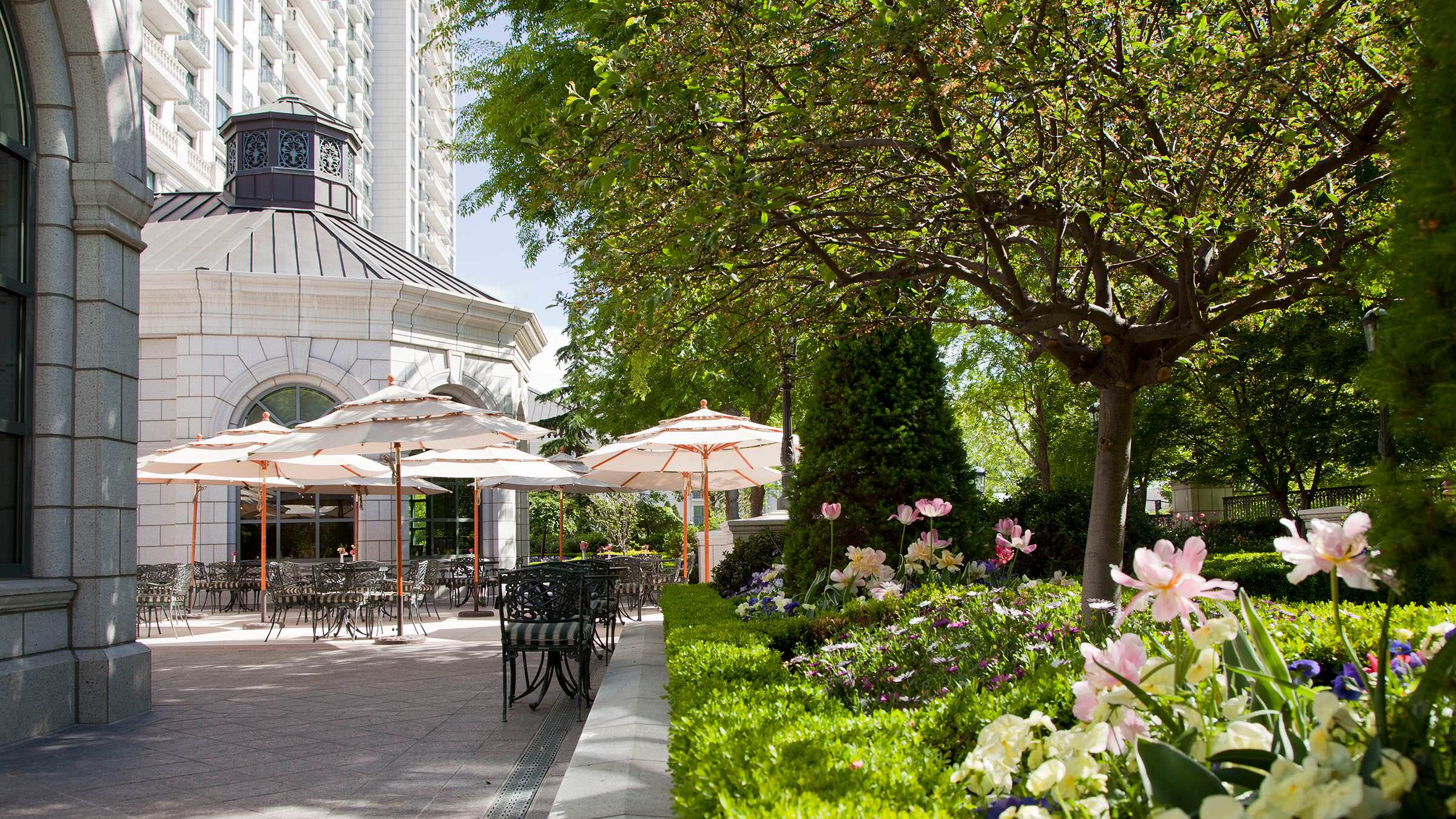 Garden Cafe patio in Salt Lake City with shade trees, flower beds, and patio dining furniture.