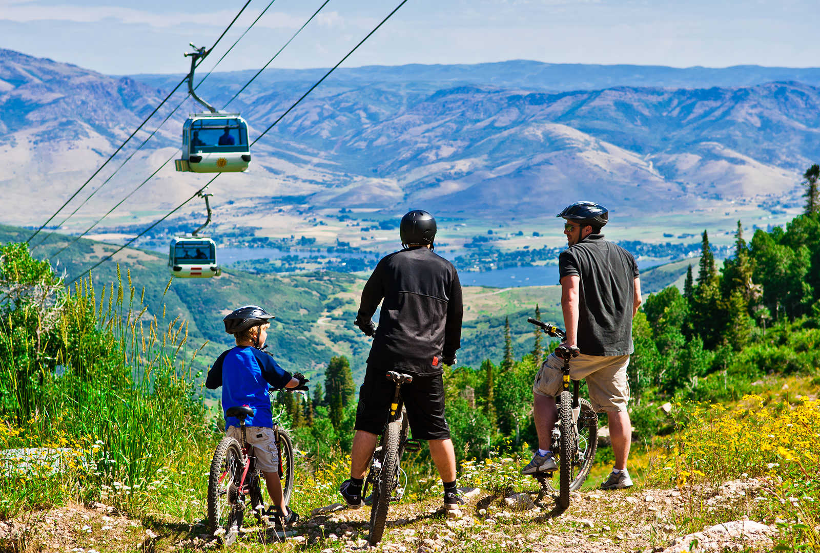 Three bikers on Snowbasin 's biking trail enjoying the breathtaking view.