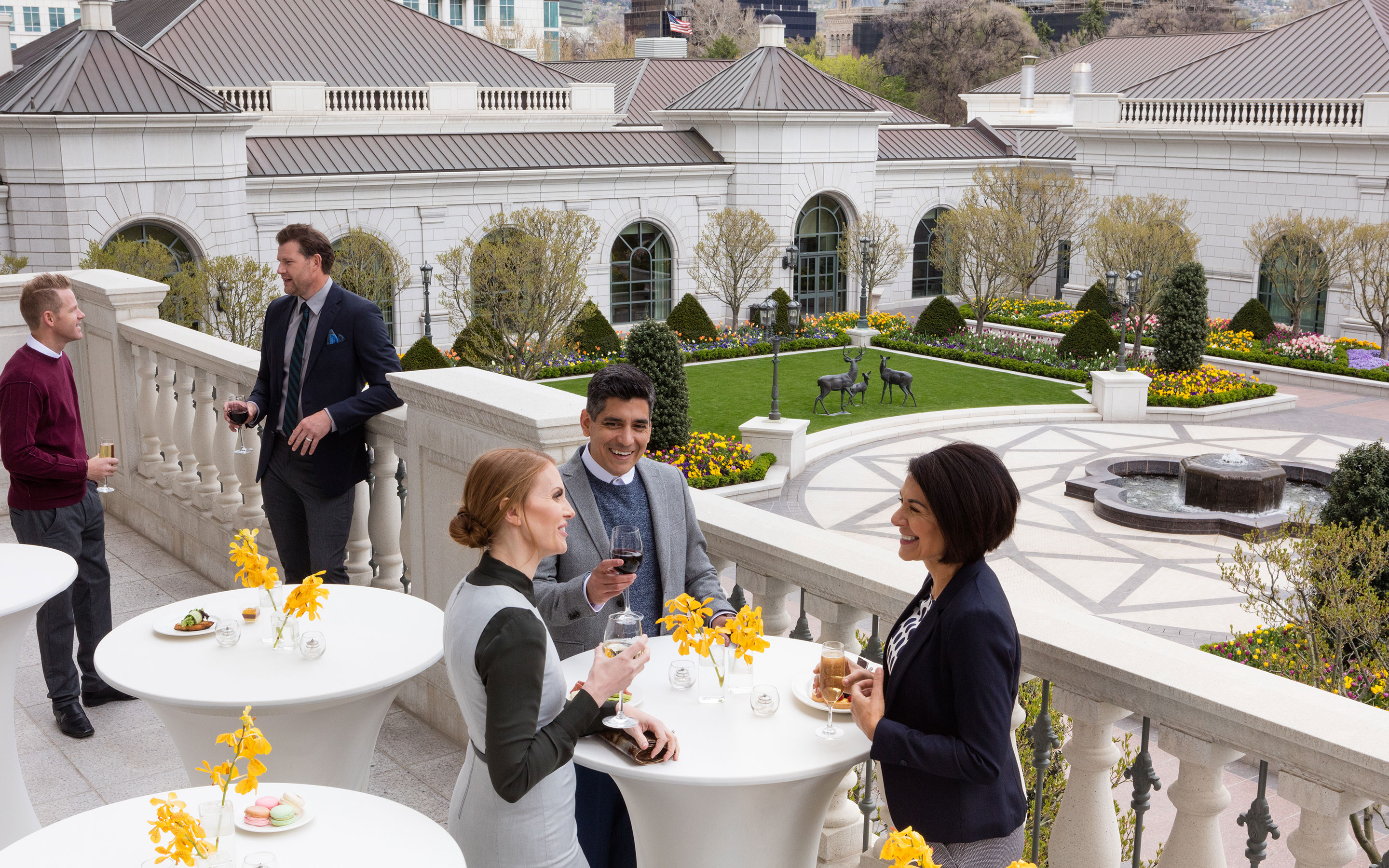Group of business colleagues at a reception talking and drinking cocktails on the balcony of the third-floor event space at The Grand America Hotel.