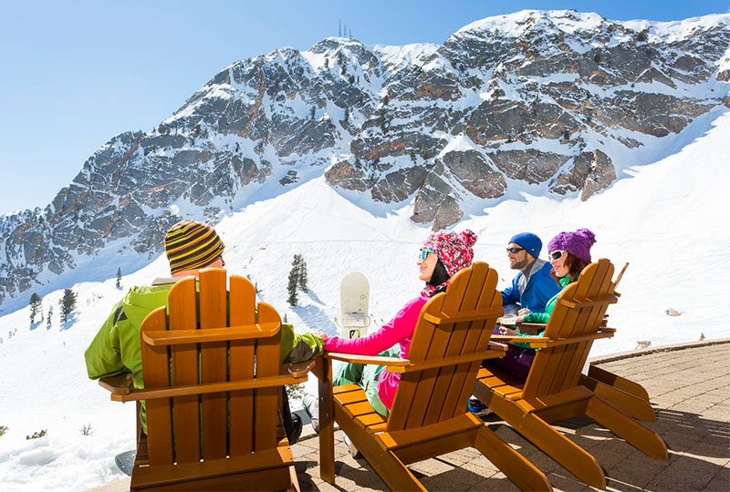 Friends lounging at Needles Lodge at the peak of Snowbasin Ski Resort in Utah.
