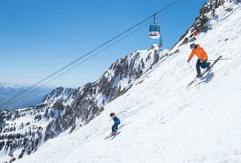 Twi skiers enjoying the snowy mountain runs at Snowbasin Resort.