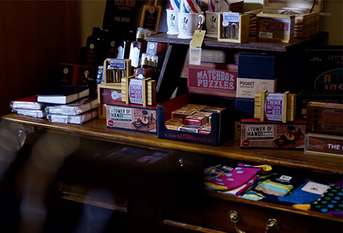 Shelf of games, notebooks, and socks inside Men's Store.