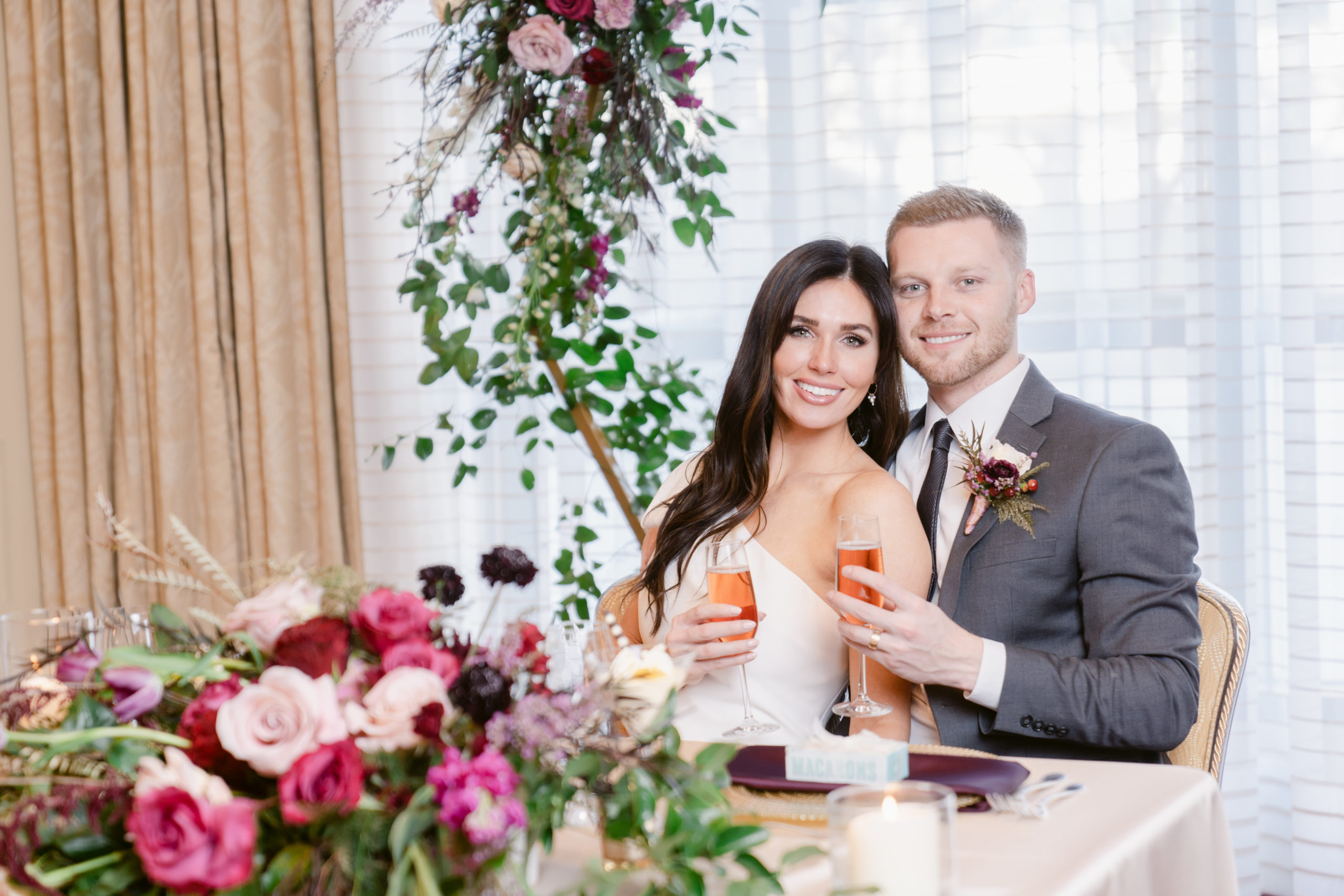Bride and Groom at their Sweetheart's Table decorated with pink and red florals..