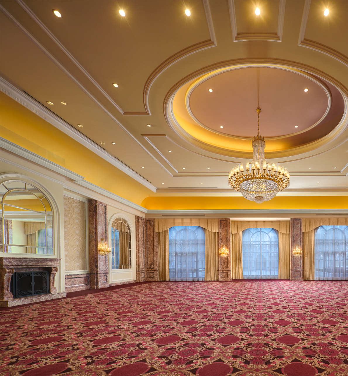 The Grand Salon meeting space with a large center chandelier and fireplace at the Grand America Hotel