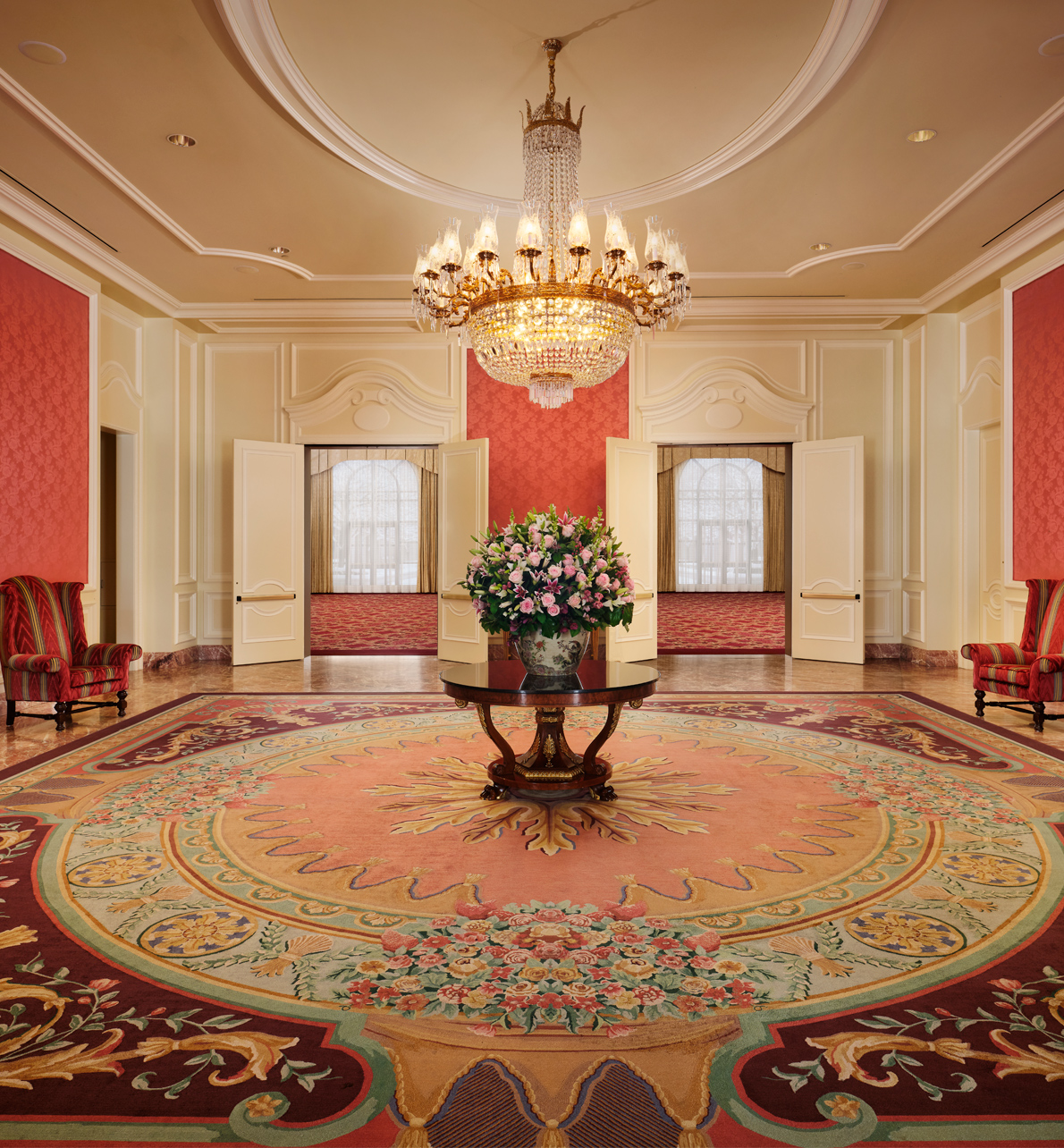 Reception area in the Grand Salon meeting space with hanging chandelier and center table with arrangement of flowers